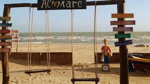 A beach swing set with a sign that reads "Ac Mare" and multiple directional signs. - Grupo Al Mare e Bellissima (Luis Correia)