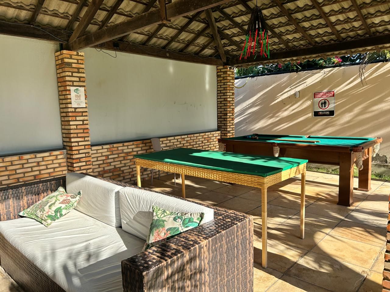 An outdoor seating area with a pool table and a sofa.