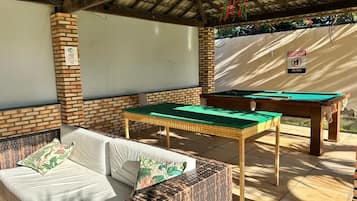 An outdoor seating area with a pool table and a sofa.