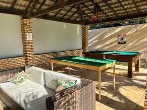 An outdoor seating area with a pool table and a sofa. - Pousada Bellíssima Itália (Luis Correia)