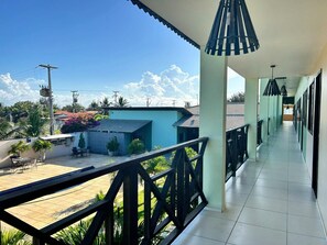 Un espacio al aire libre cubierto con suelo de baldosas, barandilla y vistas a una zona residencial con casas y vegetación.