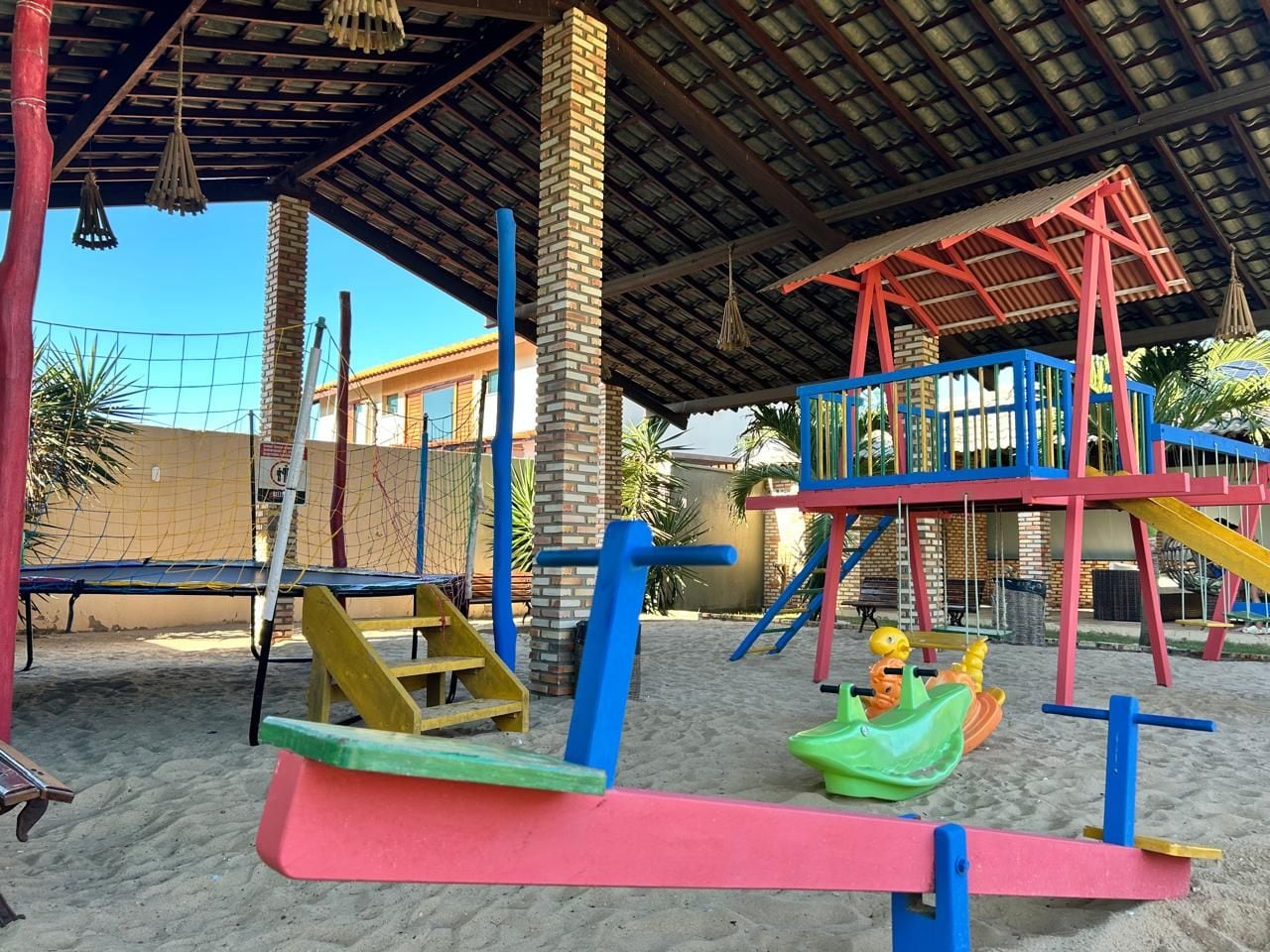 Un parque infantil con una estructura para escalar, columpios y un tobogán.