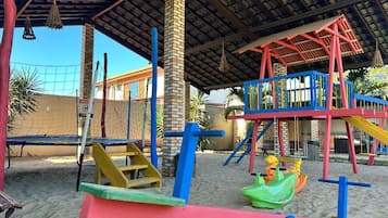 Un parque infantil con una estructura para escalar, columpios y un tobogán.