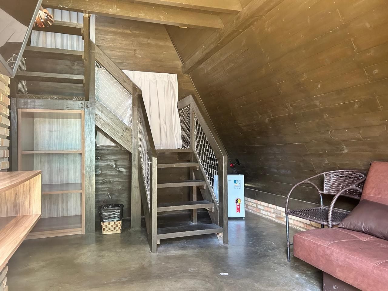 Un dormitorio tipo loft con una escalera de madera, un sofá rojo y una pequeña mesa.