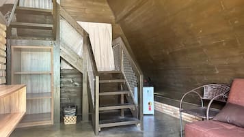 Un dormitorio tipo loft con una escalera de madera, un sofá rojo y una pequeña mesa.