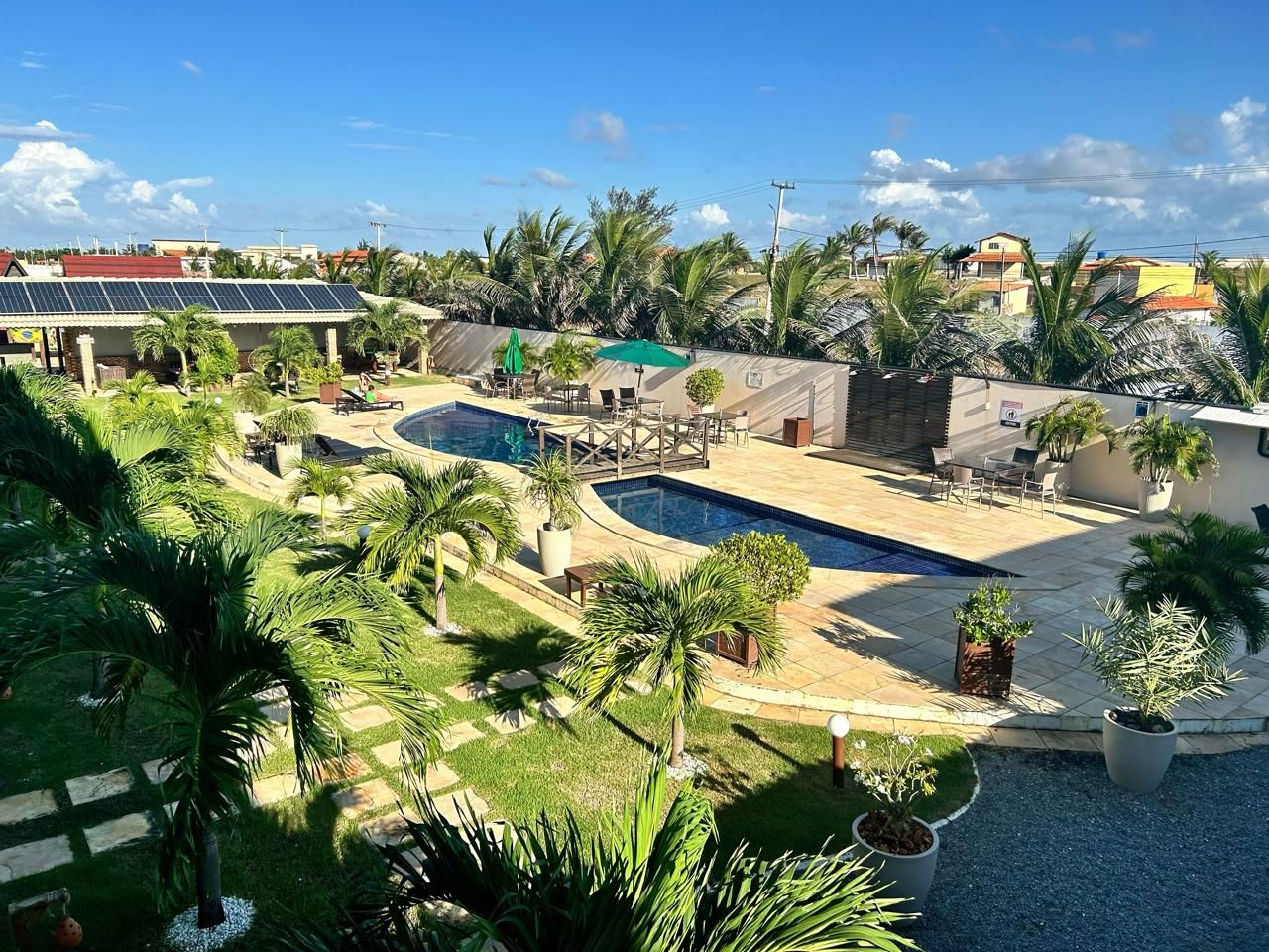 Una zona residencial con piscina, mobiliario de exterior y palmeras.