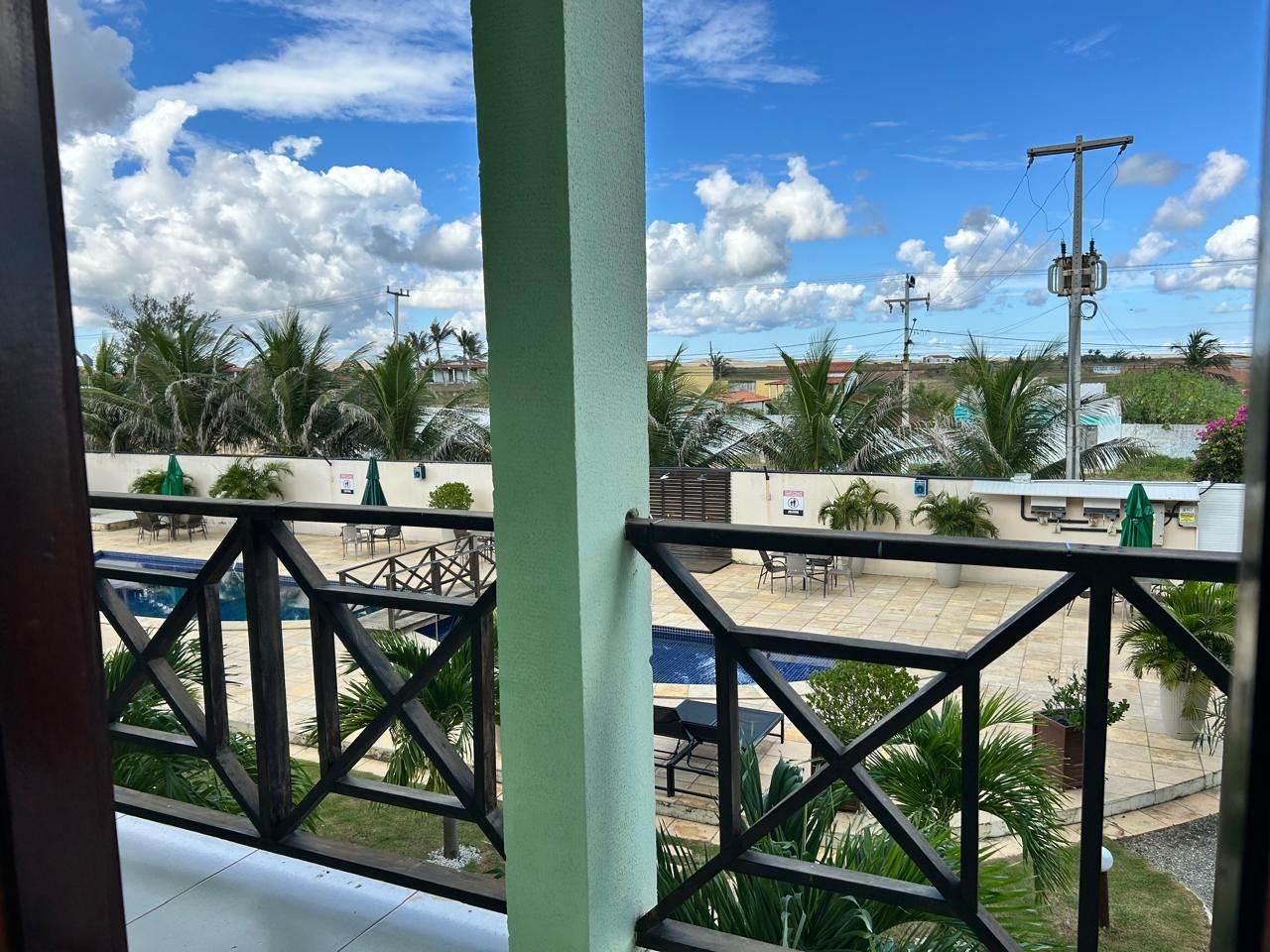 Vista de un área de piscina en la azotea con mobiliario exterior y palmeras.