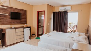 Habitación de hotel con dos camas, televisión, kitchenette y balcón.