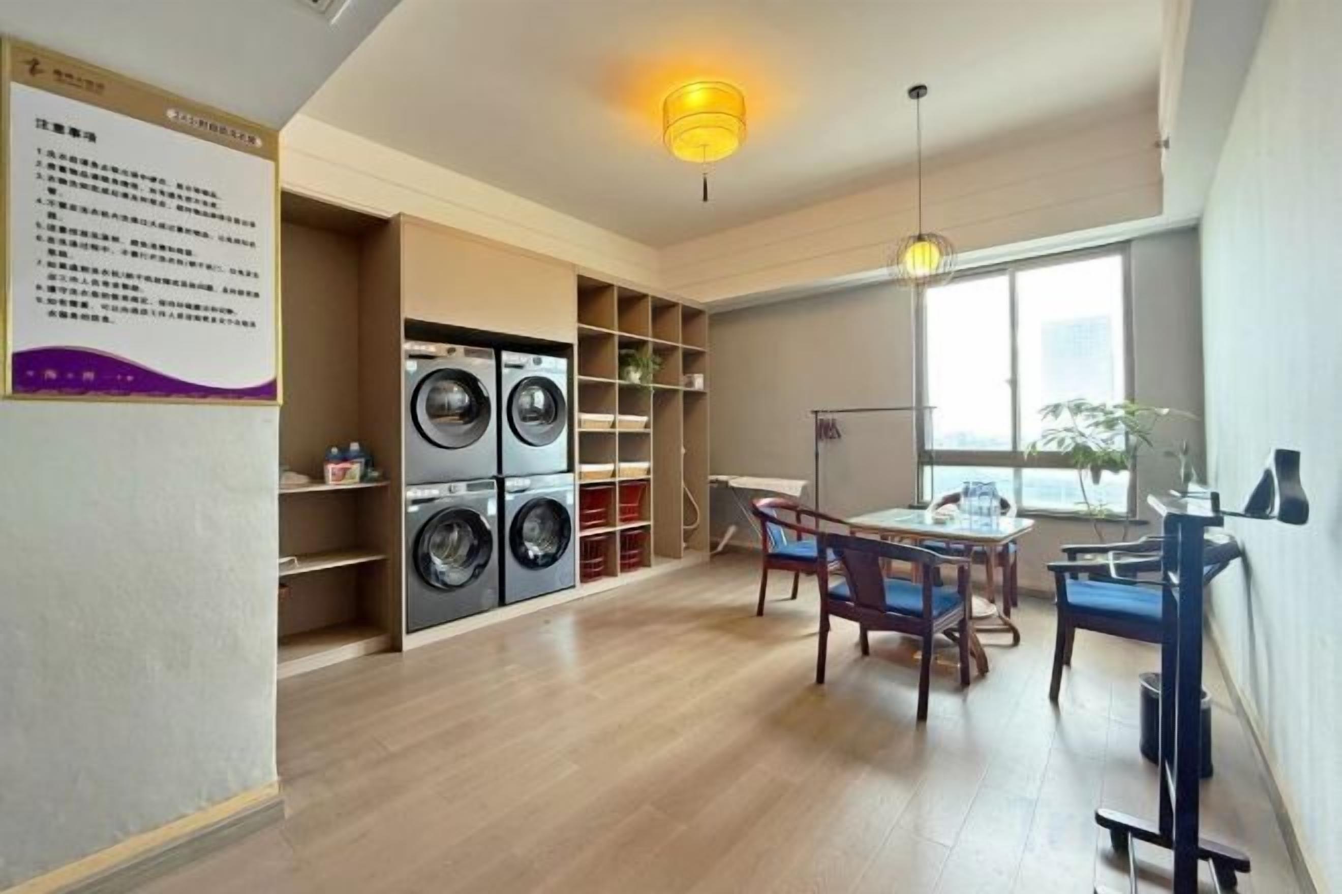 A laundry room with stacked washers and dryers, a dining area with a table and chairs, and a large window providing natural light.