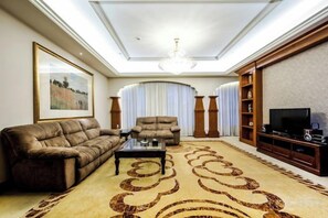 A living room with a sofa, armchair, and entertainment unit. - Haizhou Hotel (Haining)