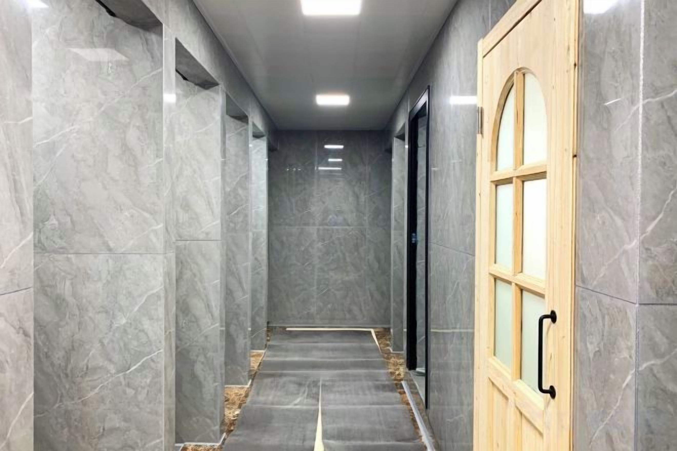 A hallway with marble walls and a wooden door with glass panels.