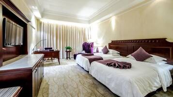 A hotel room with a bed, a desk, a chair, a television, and a window with curtains.