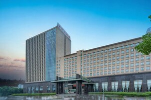 Un hotel de varios pisos con una fachada de vidrio destacada y un edificio tradicional de techo plano.