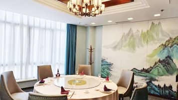 A conference room with a round table, chairs, and a chandelier.