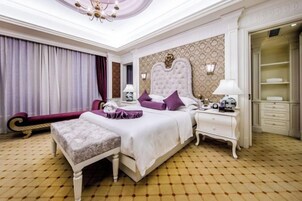 Un dormitorio amplio con una cama grande, una mesita de noche, un armario y una zona de estar con una chaise lounge.