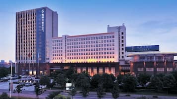 A multi-story hotel with a modern design, featuring a prominent entrance and a parking area in front.