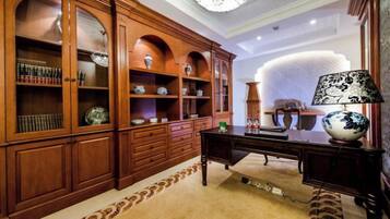 A room with a large wooden cabinet, a desk with a lamp, and a patterned rug.