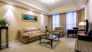 Ein Wohnzimmer mit Sofa, Sessel, Couchtisch und Fernseher.