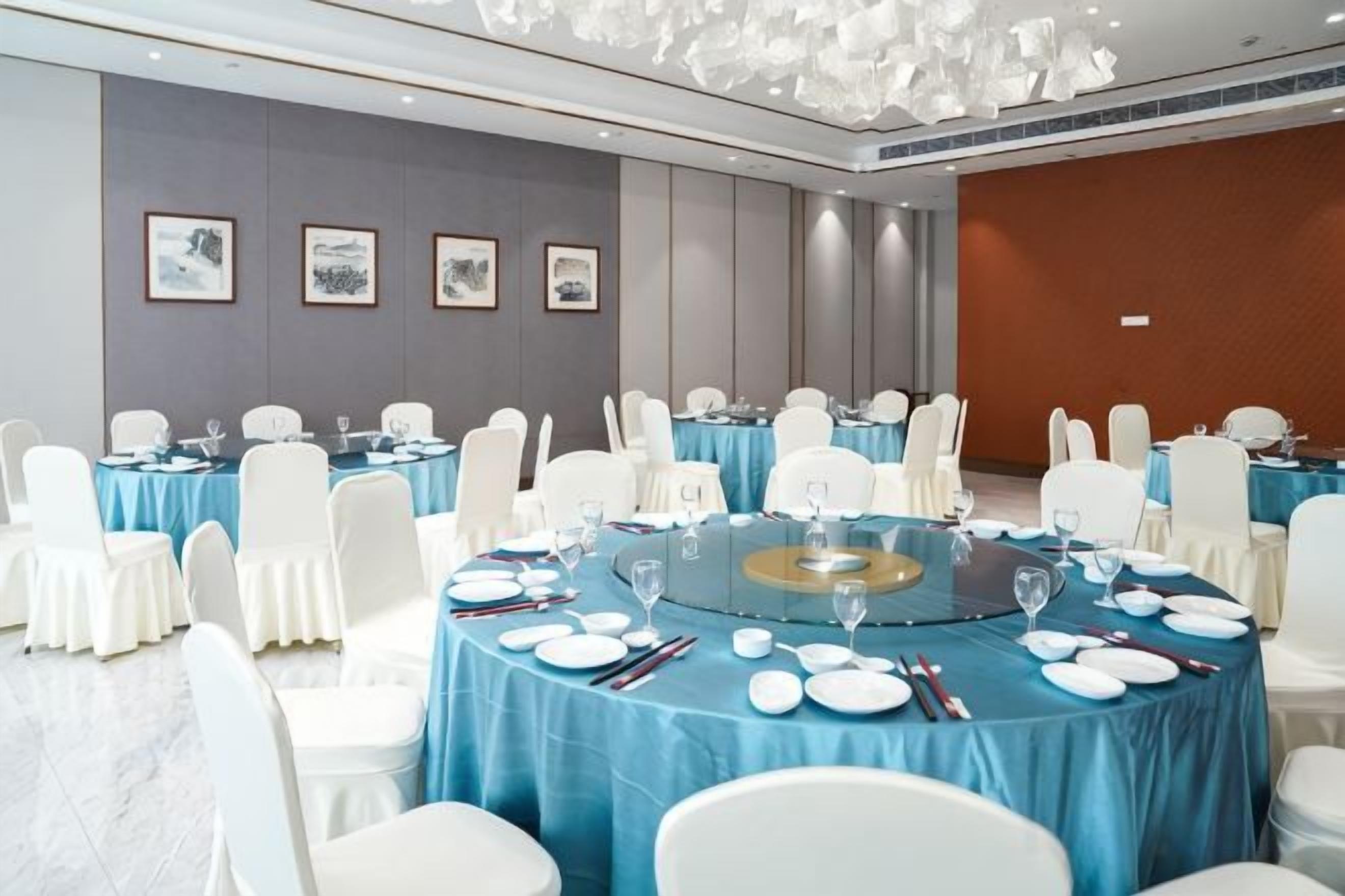 A conference room with round tables, white chairs, and blue tablecloths.
