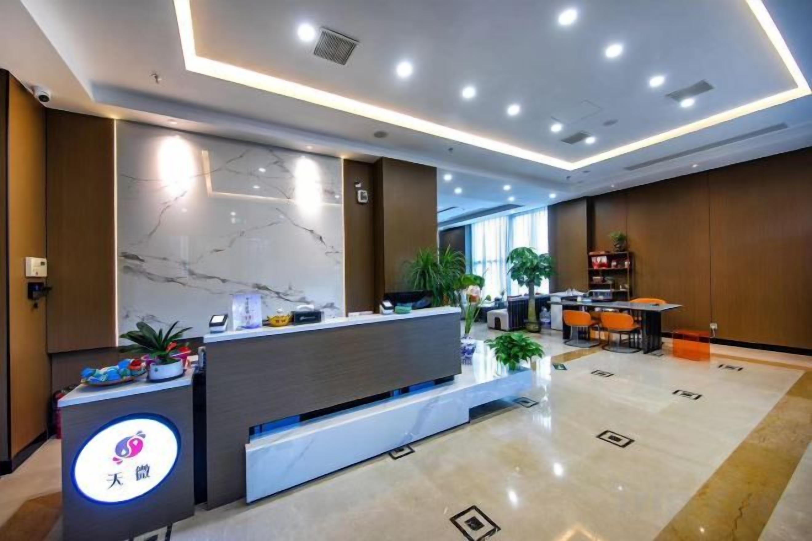 A hotel reception area with a marble counter, seating area, and a modern ceiling design.