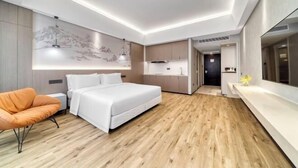 Una habitación de hotel moderna con cama, zona de estar, cocina y baño.