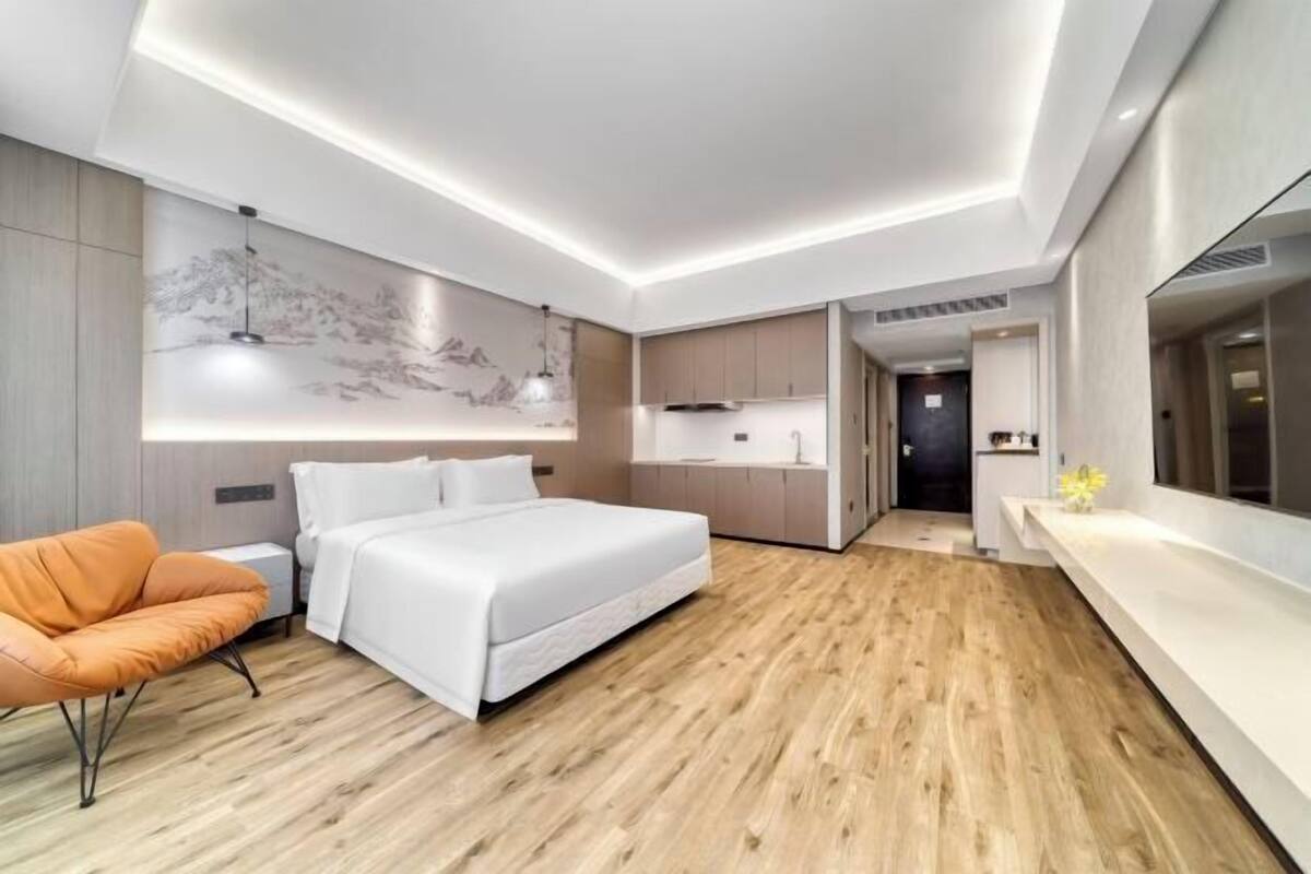 Moderni hotellihuone, jossa on sänky, oleskelualue, keittiö ja kylpyhuone.