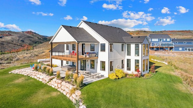 A modern two-story house with a balcony, a deck, and a well-maintained lawn. - Raspberry Retreat ~ Private Hot Tub ~ Indoor Pickleball (Garden City)