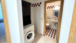 Un baño pequeño con lavadora, lavamanos y suelo a cuadros.