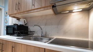 A modern kitchen with wooden cabinets, a stainless steel sink, a black microwave, and a digital clock displaying 0:00. - Central Athens Apt Patio View by MPS (Athina)