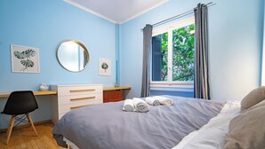 A bedroom with a bed, a desk, a chair, a dresser, a window with curtains, and artwork on the walls. - Central Athens Apt Patio View by MPS (Athina)