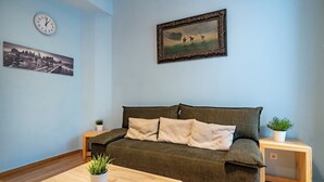 A living room with a sofa, a coffee table, a clock, and framed artwork on the wall. - Central Athens Apt Patio View by MPS (Athina)