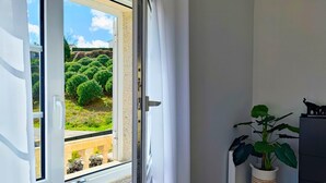 A room with a large window, a potted plant, and a radiator.