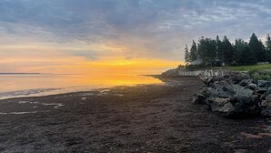 Une plage bordée d’une côte rocheuse et d’une clôture en bois.
