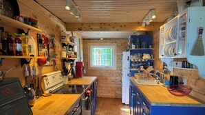 Une cuisine compacte aux murs en bois, dotée d’un îlot central et de divers appareils de cuisine.