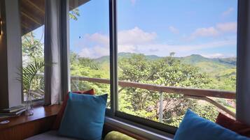 A room with a large window overlooking a mountainous landscape.