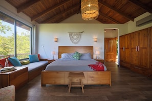 Een ruime slaapkamer met een groot bed, houten meubels en uitzicht door een raam.
