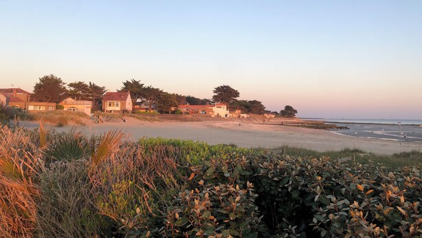 Ein Küstenwohngebiet mit Häusern, einem Strand und blauem Himmel.
