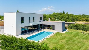 A modern two-story house with a swimming pool, a covered patio, and a well-maintained lawn. - Villa Marichi – Countryside Retreat w/Pool & Sauna (Marići)