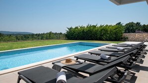 A swimming pool with lounge chairs and a view of the landscape. - Villa Marichi – Countryside Retreat w/Pool & Sauna (Marići)