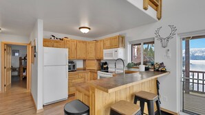 Una cocina moderna con armarios de madera, una isla central con taburetes, un refrigerador, un microondas y un lavamanos.