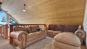 Una habitación acogedora con techo de madera, un sofá de cuero y un sillón mullido.