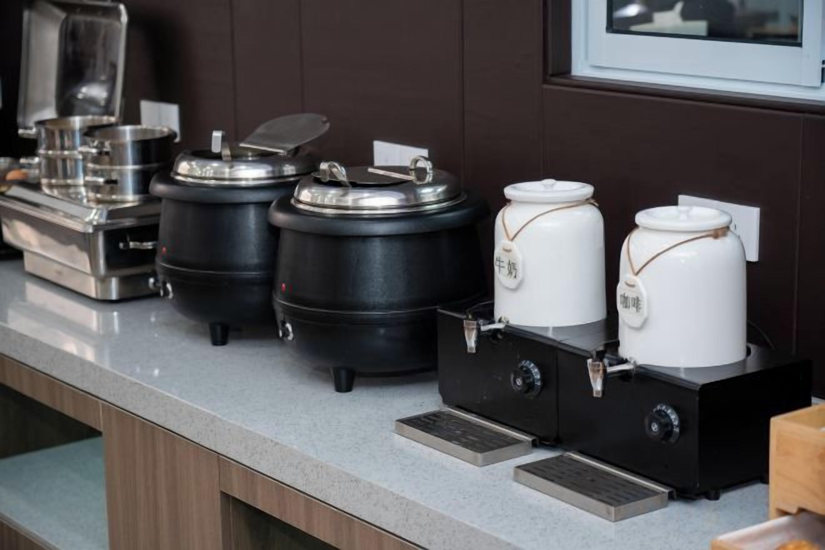 A buffet setup with various food containers and a coffee machine.
