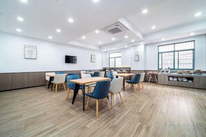 A spacious room with wooden flooring, multiple tables and chairs, a television, and large windows. - Hanting Hotel (Shanghai Lin'gang New City) (Shanghai)