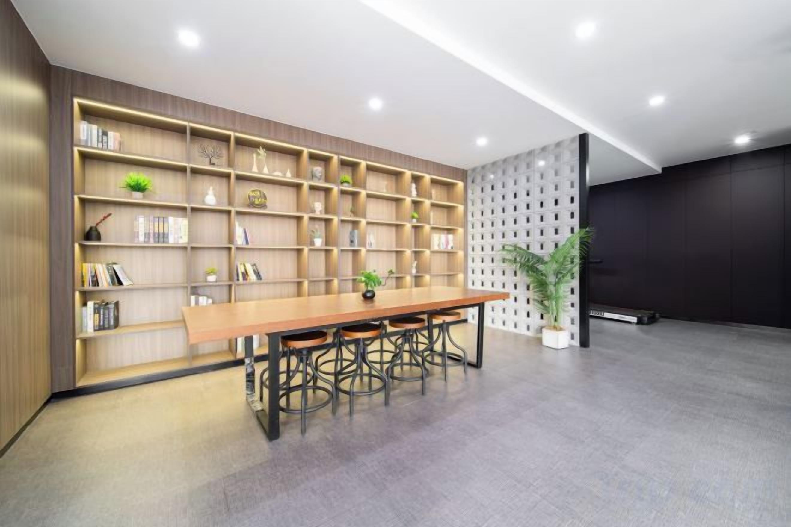 Un intérieur moderne avec une longue table et des chaises en bois, une bibliothèque et une plante en pot.