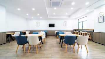 A conference room with tables and chairs, a flat-screen TV, and a window.