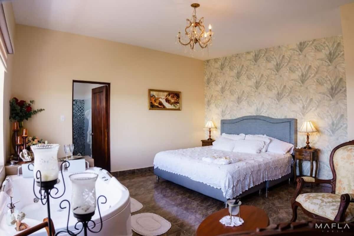 Une chambre à coucher avec un grand lit, un lustre, un tableau et un papier peint à motifs.