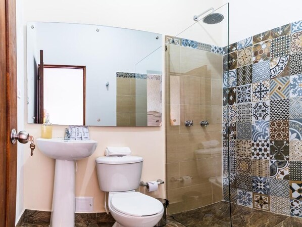 A bathroom with a white sink, toilet, and a shower with patterned tiles.