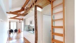 Una cucina moderna con mobili bianchi, travi a cassetto in legno e pavimento a scacchi bianconero.