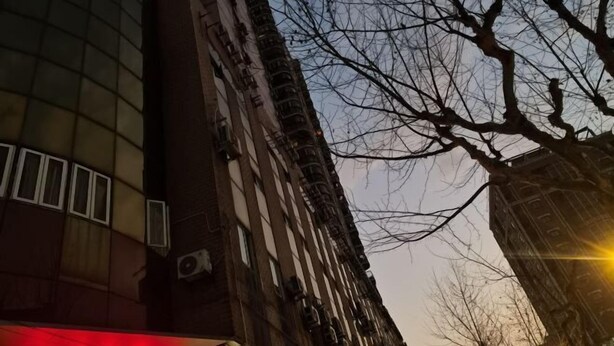 En høj bygning med moderne glasfacade og en traditionel murstensstruktur.