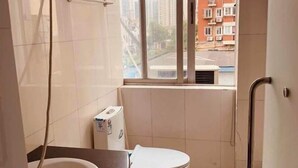Et badeværelse med toilet, vask og et vindue.